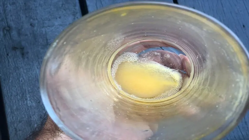Undissolved powder at the bottom of a glass of Zipfizz orange soda