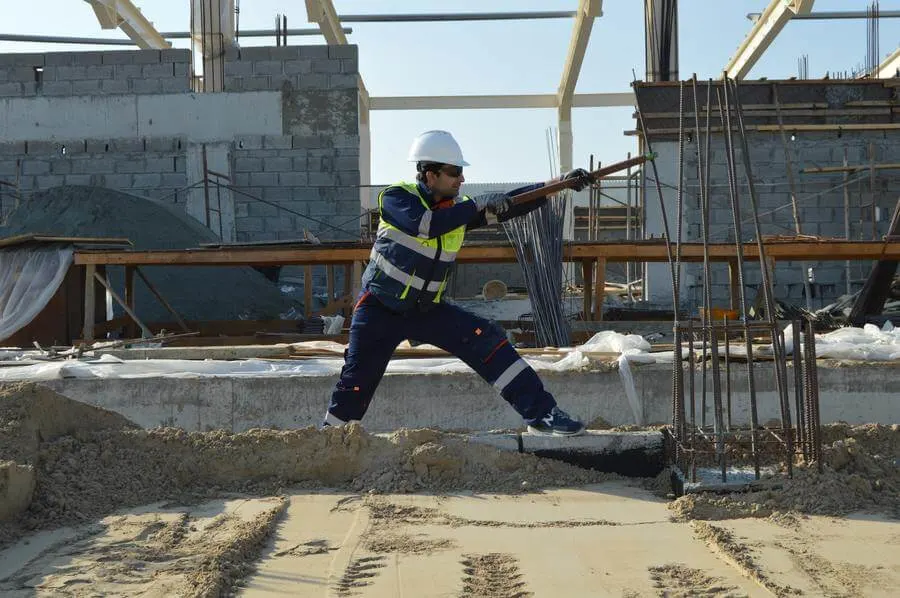 A construction worker pulling on some metal rods at work