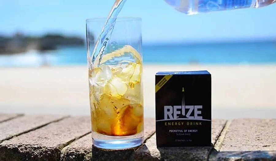 A packet of REIZE next to a glass of REIZE energy drink 