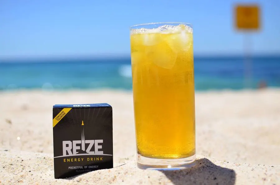 Glass of REIZE Energy Drink on the beach.