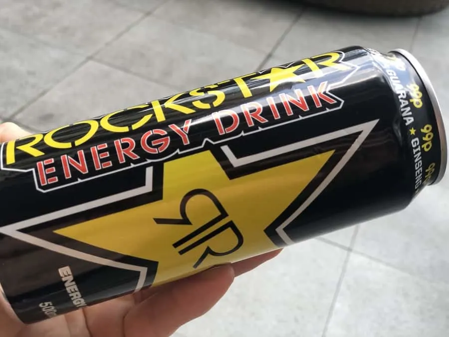 Rockstar Energy Drink can being held to the side by a left hand