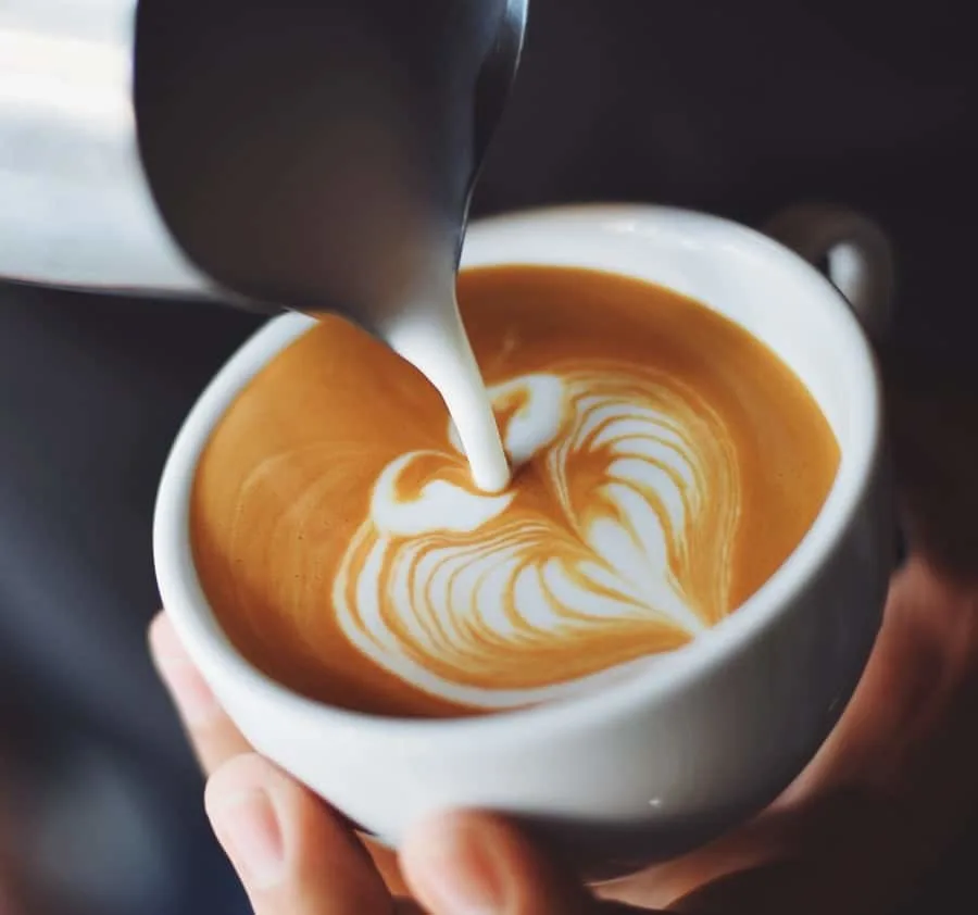 Milk being poured into a cup of coffee forming latte art