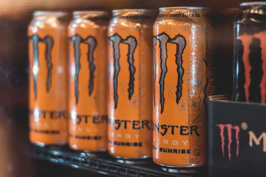 Monster energy drinks lined up on a shelf. 