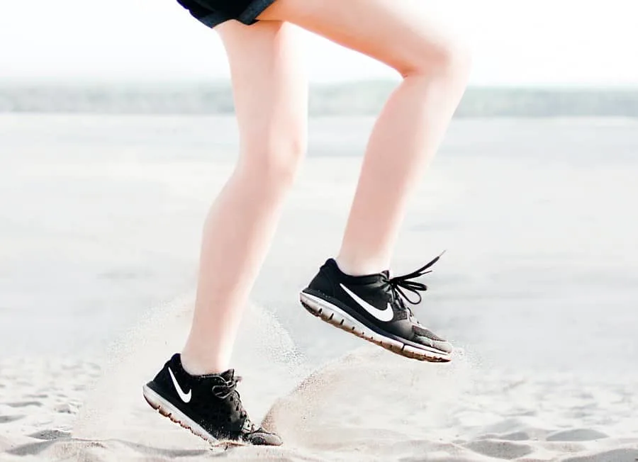 Woman with black nike shoes running on the sand