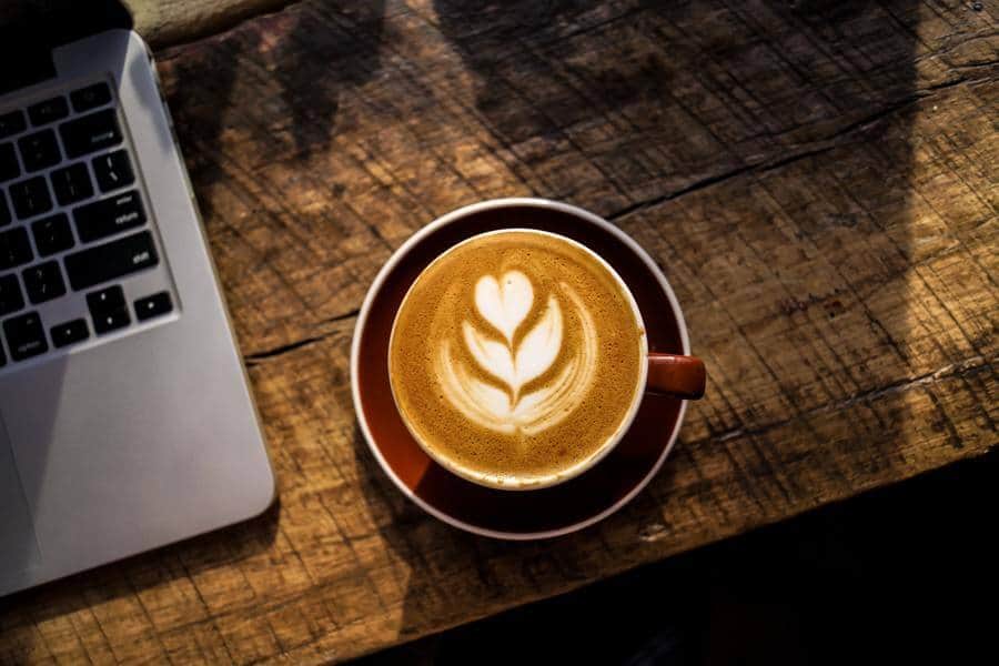 Cup of coffee next to a laptop on a table