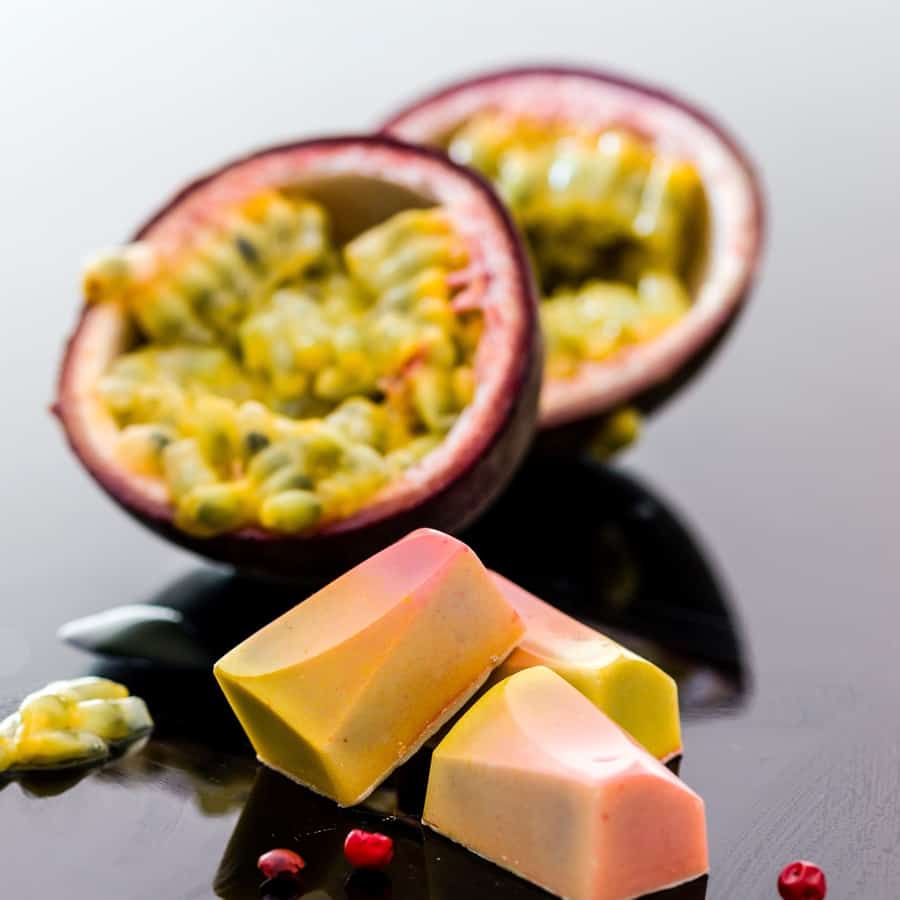 Passion Fruit and passion fruit slices on a reflective surfacce.