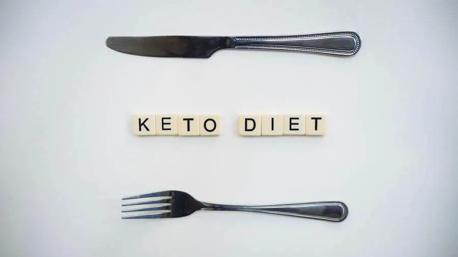 Scrabble tiles spelling out keto diet arranged between a fork and knife.