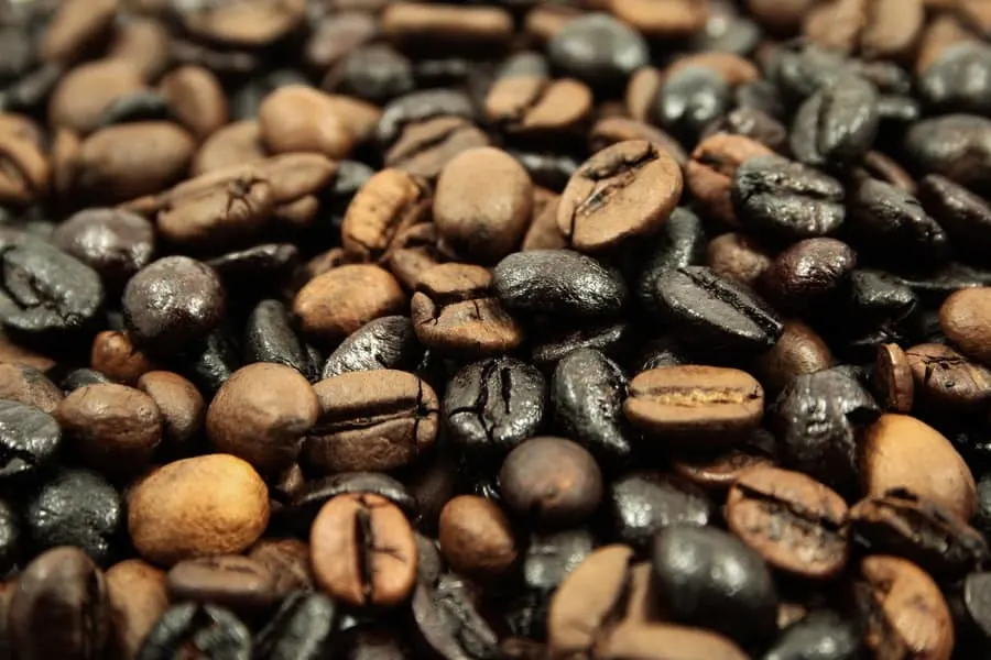 Brown and black coffee beans piled together. 