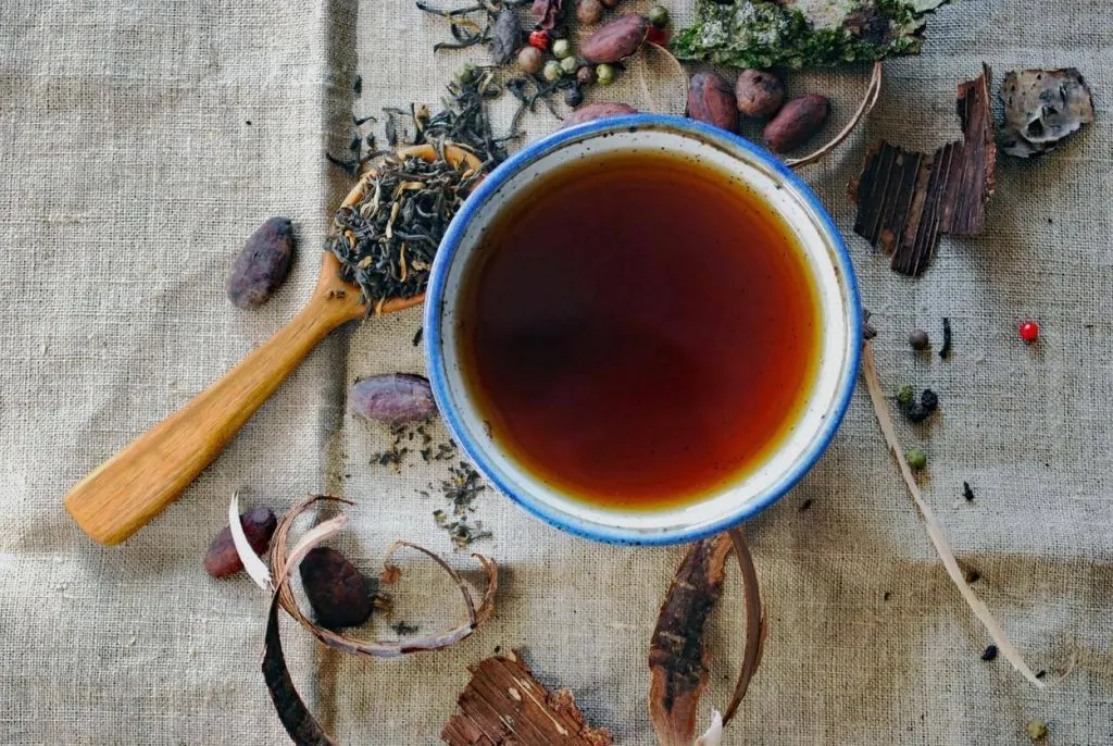 A picture of black tea with herbs surrounding the mug
