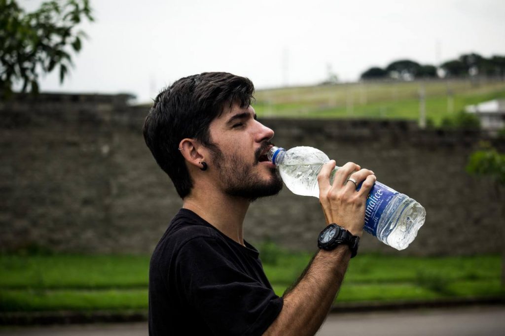 A picture of a man wearing black shirt drinking water
