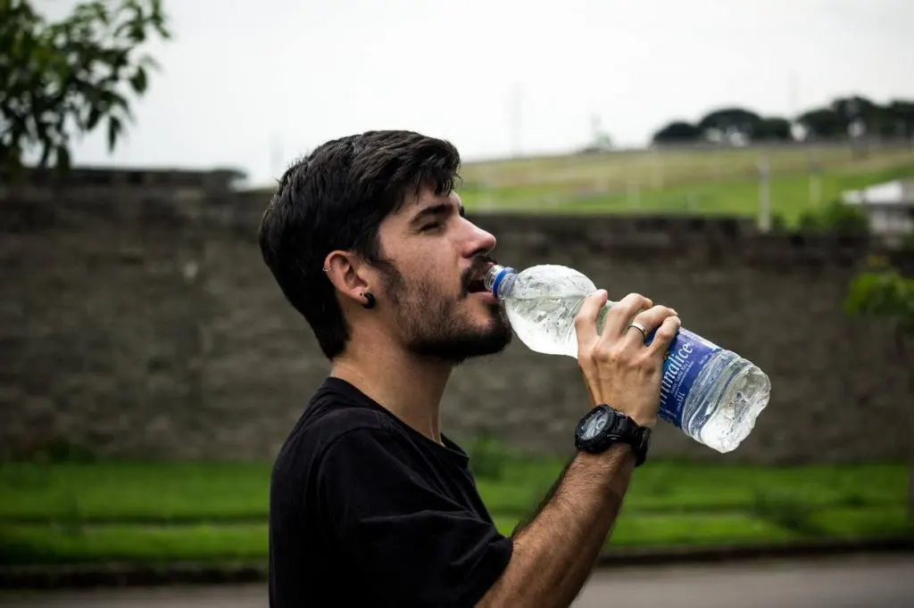 A picture of a man wearing black shirt drinking water
