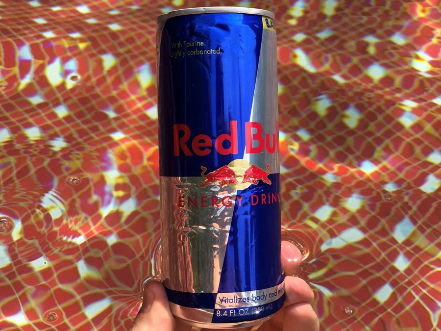 A hand holding a can of Red Bull.