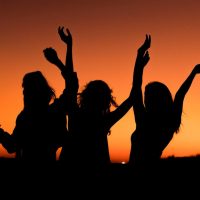 A group of girls having fun with the sunset as the background.