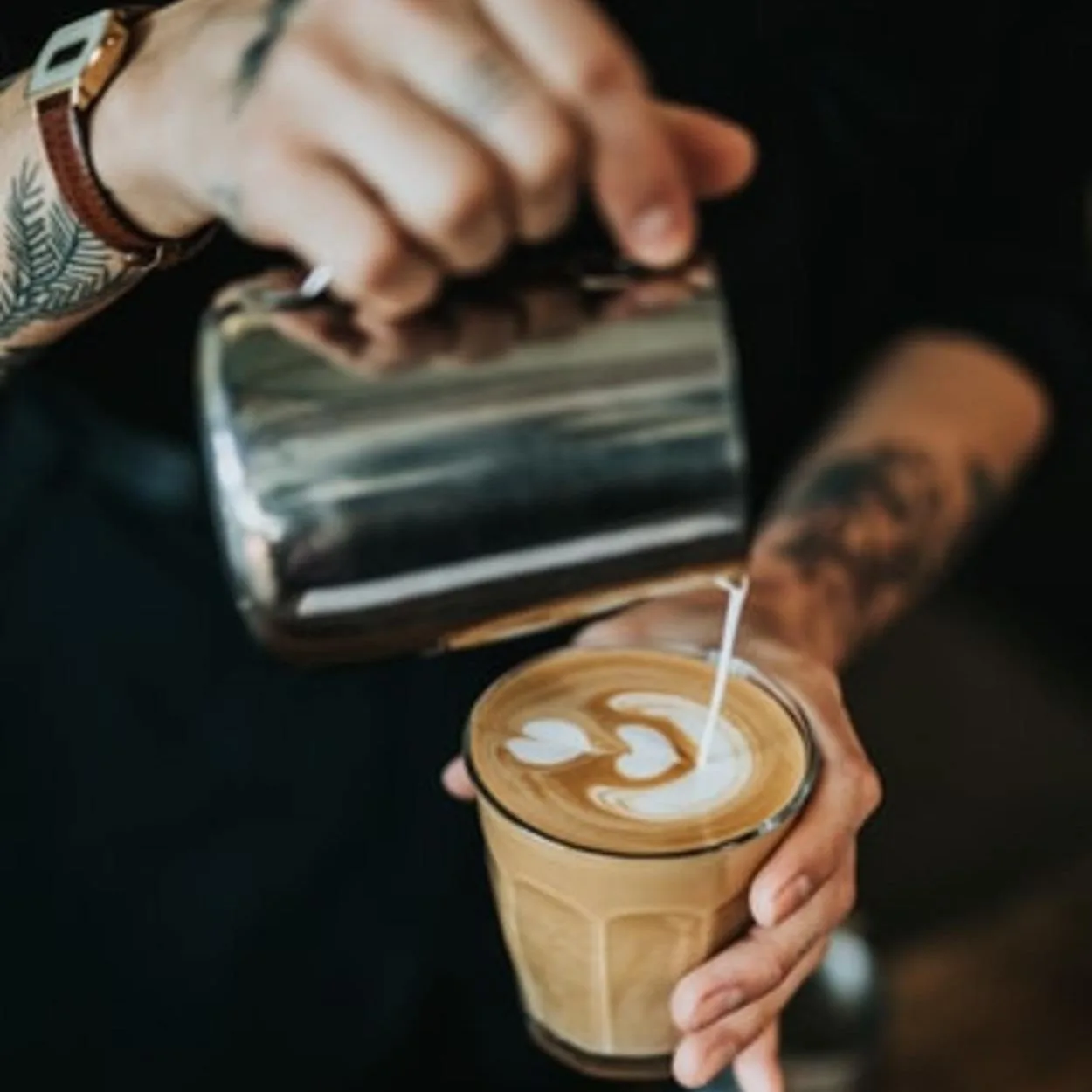A barista pouring coffee in a cup.