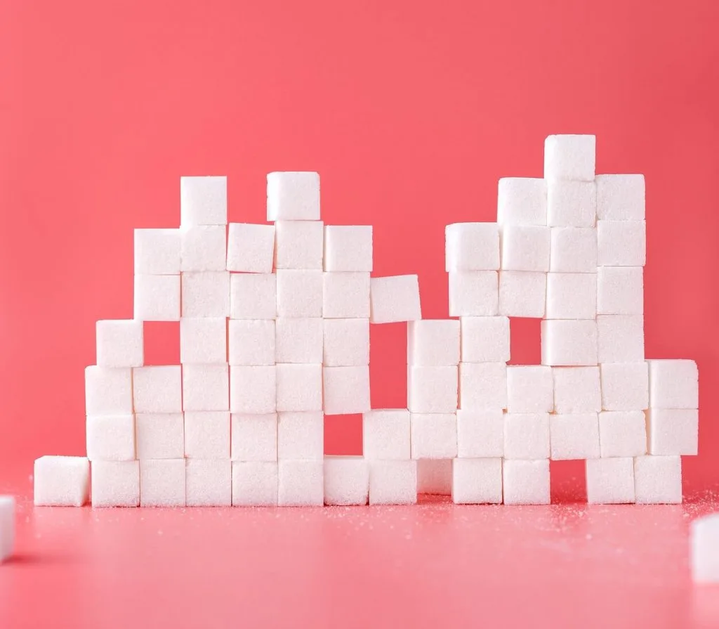 Sugar cubes stacked atop each other against a vibrant red background. 