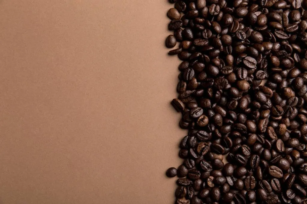 Coffee beans at one side of a brown background. 