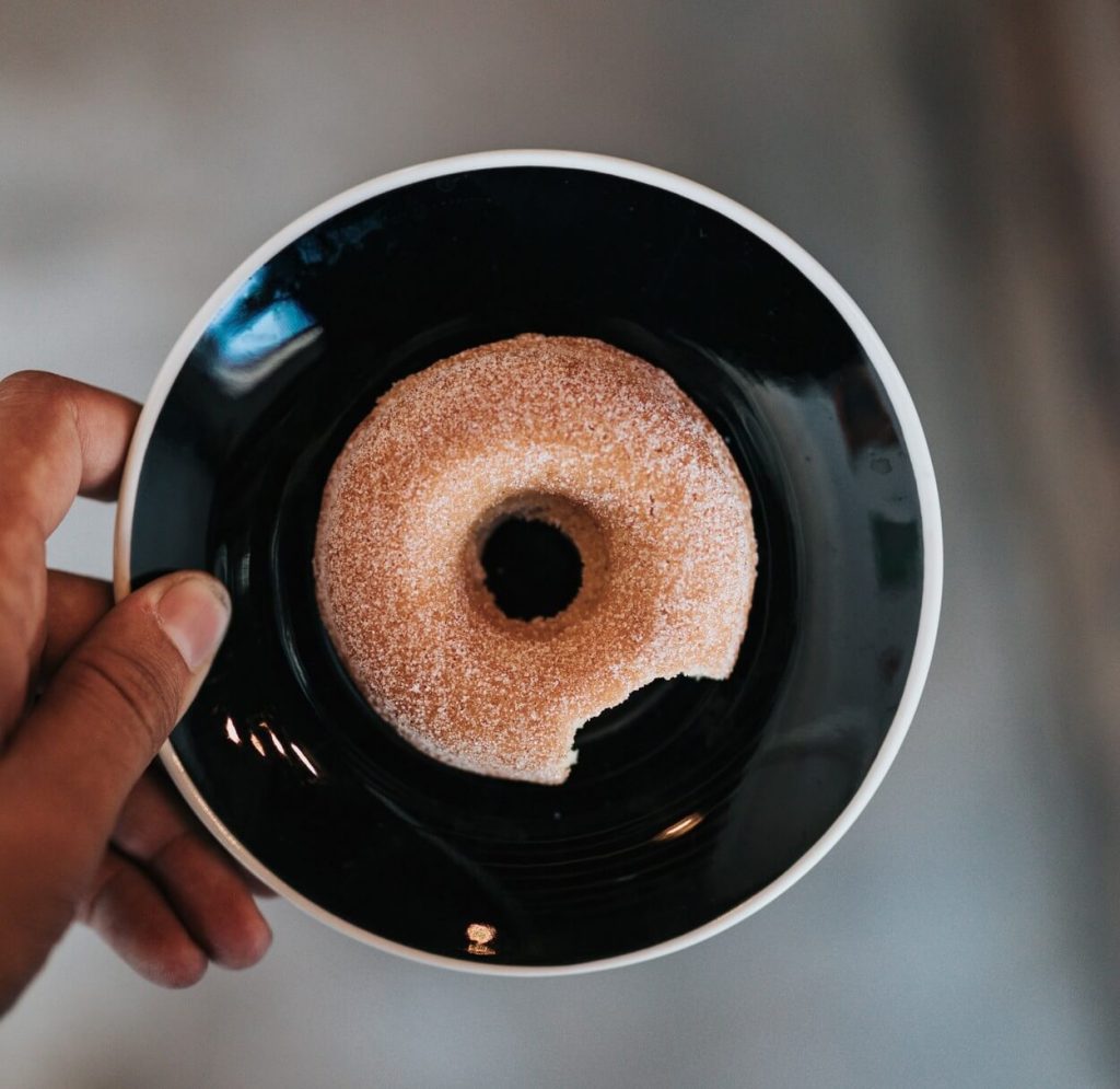 A half-bitten doughnut on a plate. 