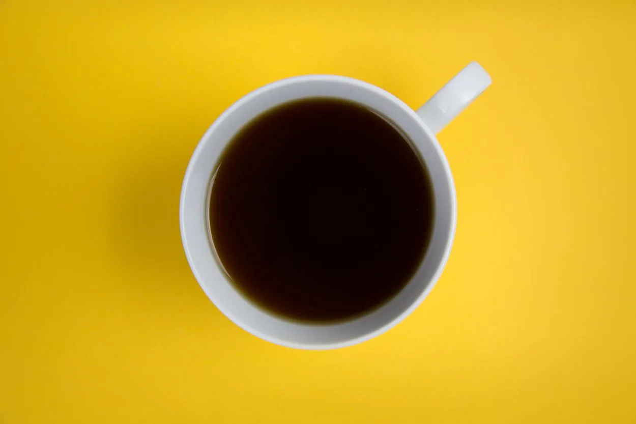 A cup of coffee against yellow background.
