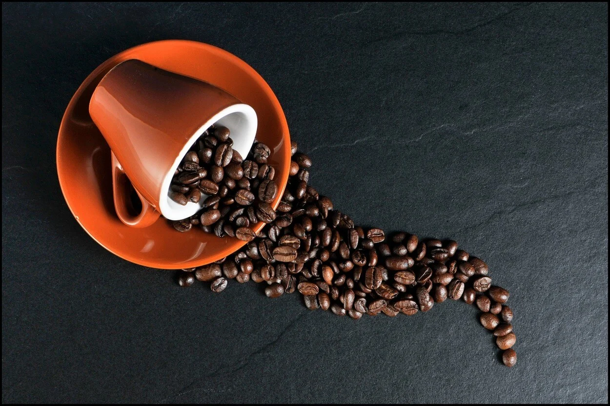 Coffee beans spilling from cup.