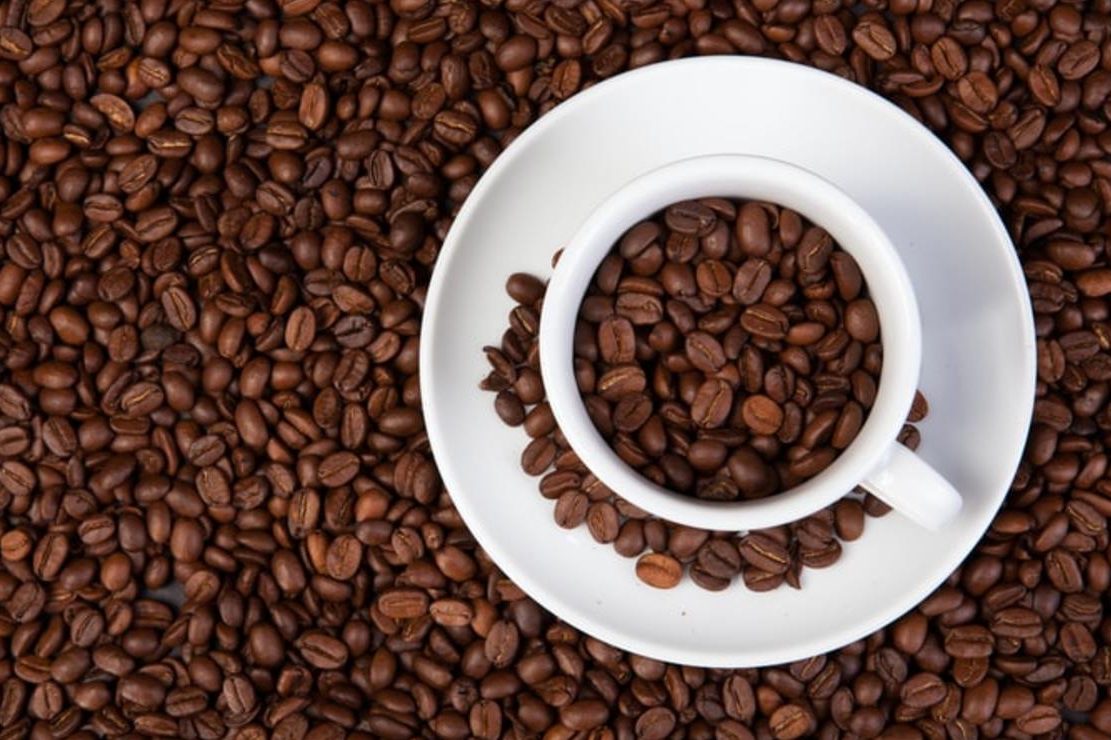 Coffee cup surrounded by coffee beans. 