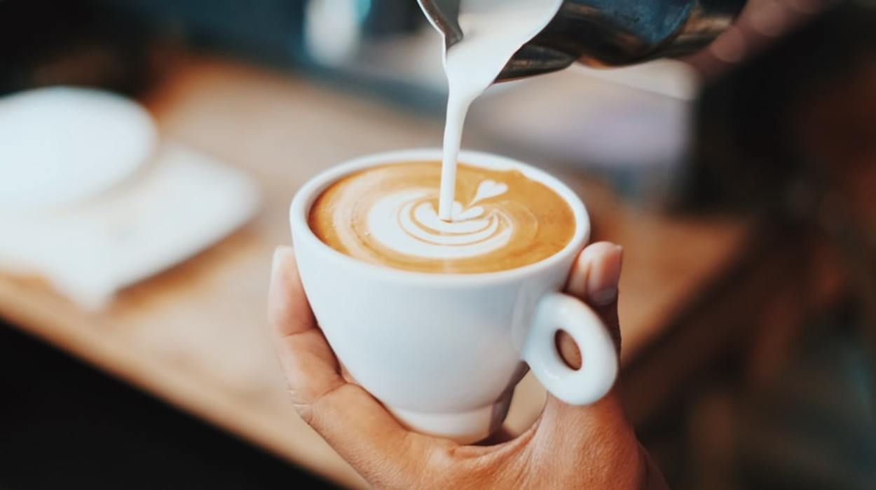 Milk being poured into a cup of coffee. 
