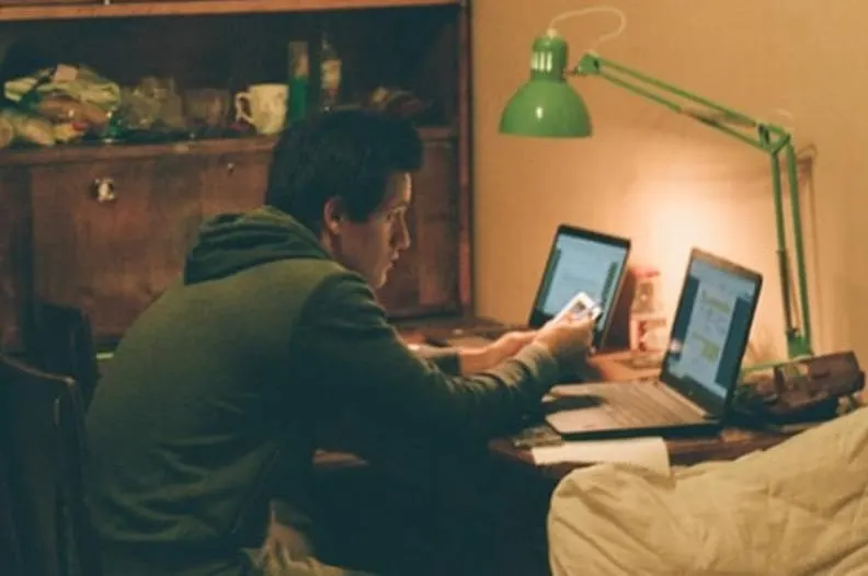 A man sitting in front of two laptop. 