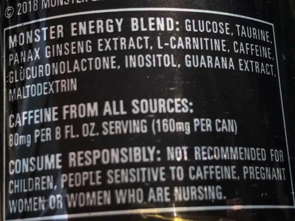 A list of ingredients, caffeine content, and some warnings printed at the back of a can of Monster Energy.