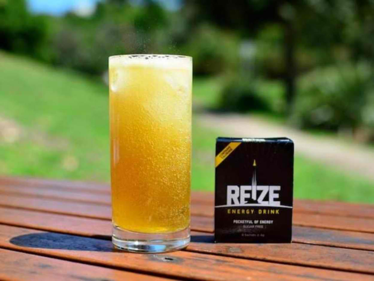 A glass and a pack of REIZE Energy Drink.
