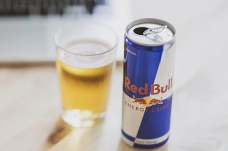 A can of Red Bull next to a glass.