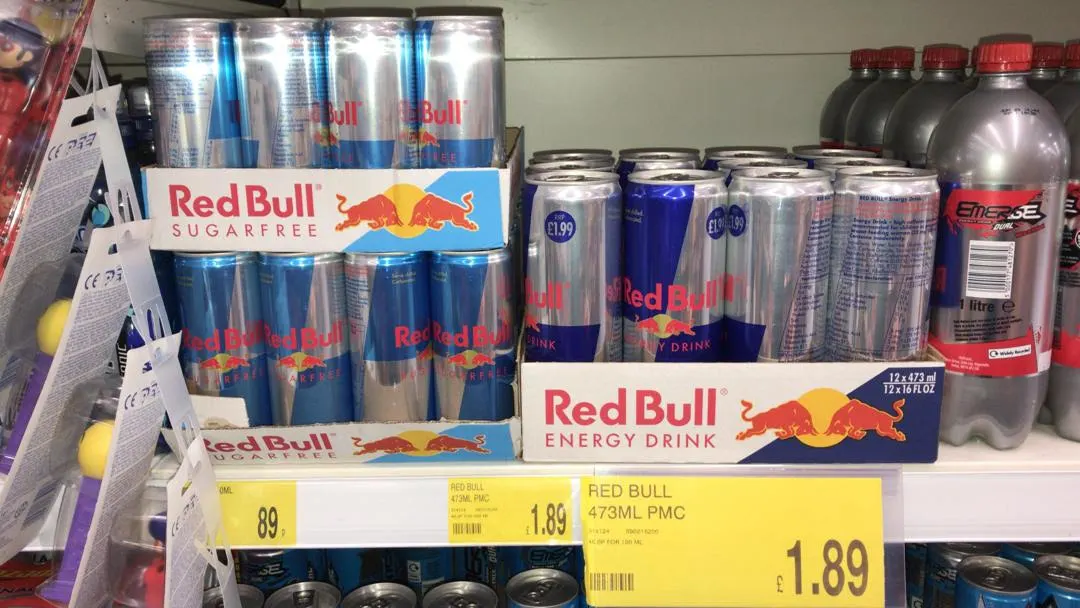 Packs of classic Red Bull energy drink and Red Bull Sugarfree displayed on a shelf