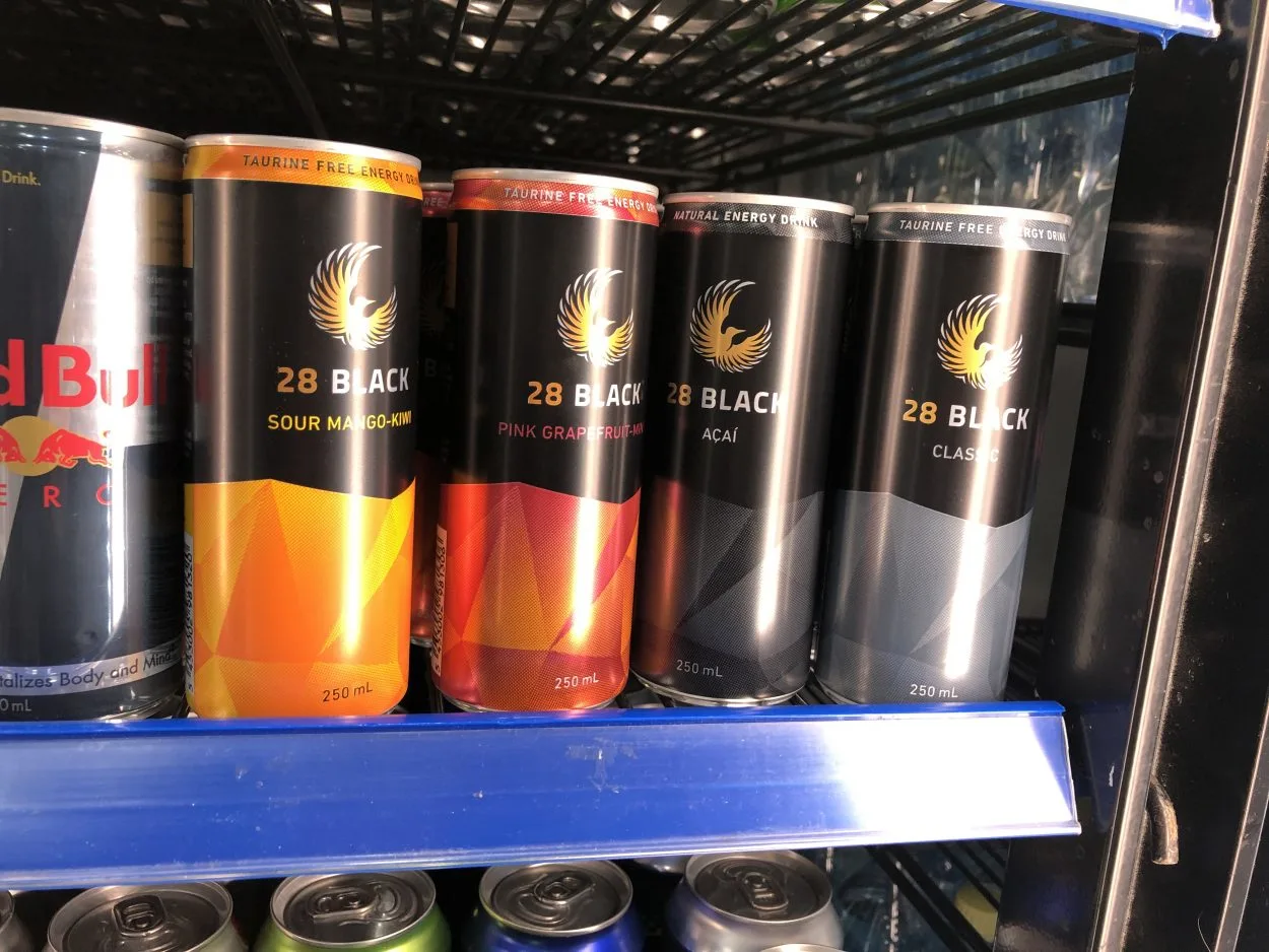 Different flavors of 28 Black Energy Drink displayed on a fridge.