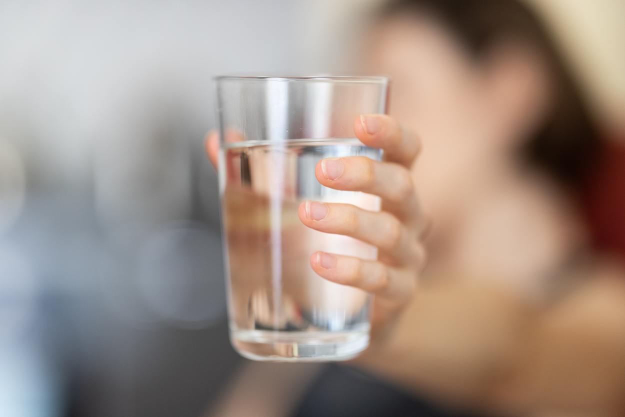 Woman holding glass of water.